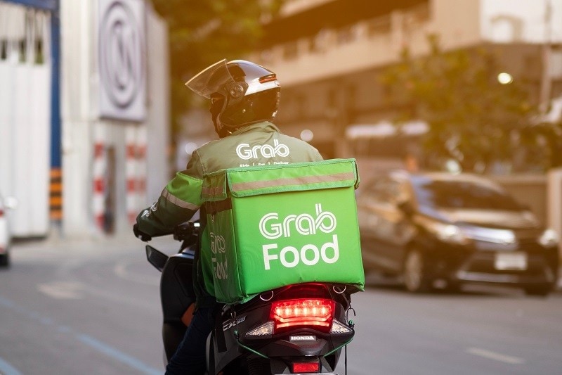 A Grab delivery rider en route on his motorcycle A Grab delivery rider en route on his motorcycle