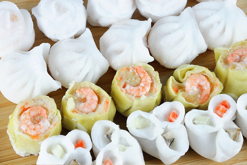 Assorted frozen dumplings on a wooden surface. Assorted frozen dumplings on a wooden surface.