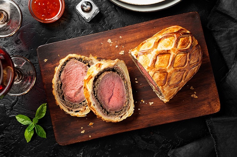 Sliced beef wellington on a wooden board. Sliced beef wellington on a wooden board.
