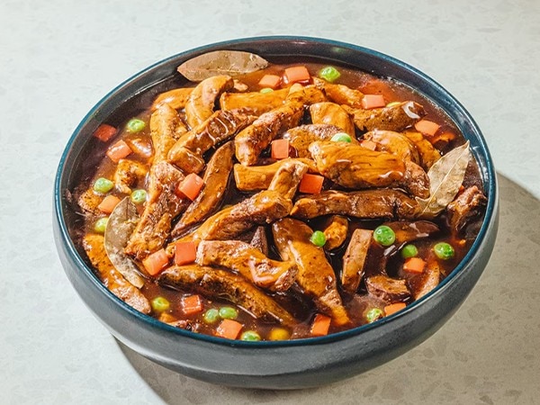 Igado with sliced liver and bell peppers in a dark serving bowl. 