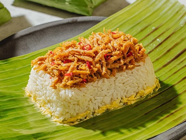 Chicken patir on top of rice served over a banana leaf. 