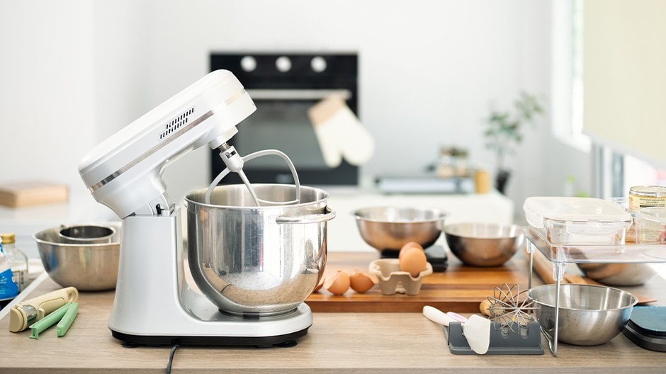 Basic baking equipment, including an electric mixer, oven, whisk, and bowls.