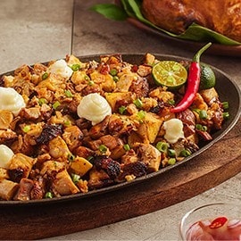 Chicken inasal sisig topped with mayonnaise on a sizzling plate. Chicken inasal sisig topped with mayonnaise on a sizzling plate.