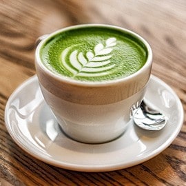 Hot matcha latte in a white cup. Hot matcha latte in a white cup.