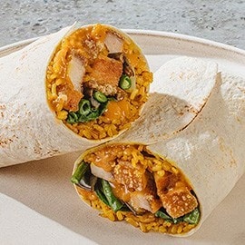 Lechon kawali kare-kare burrito on a white plate. Lechon kawali kare-kare burrito on a white plate.