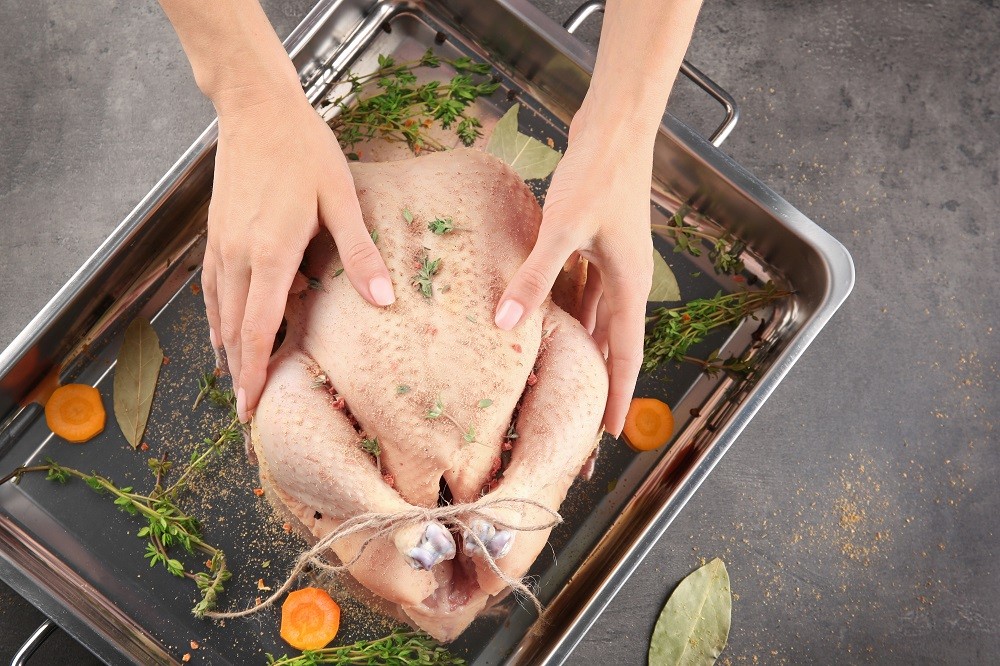 Whole uncooked turkey on a roasting pan with herbs and spices Whole uncooked turkey on a roasting pan with herbs and spices