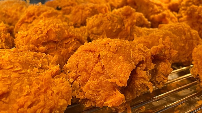 Golden fried chicken sitting on a rack after frying. 