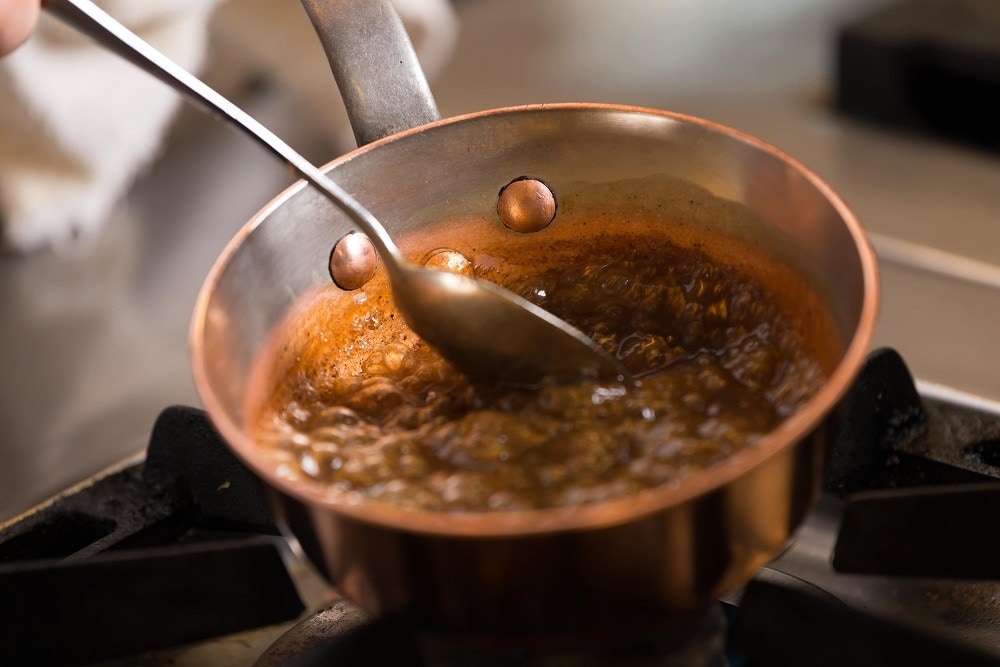 A chef is making caramel sauce in a pan A chef is making caramel sauce in a pan