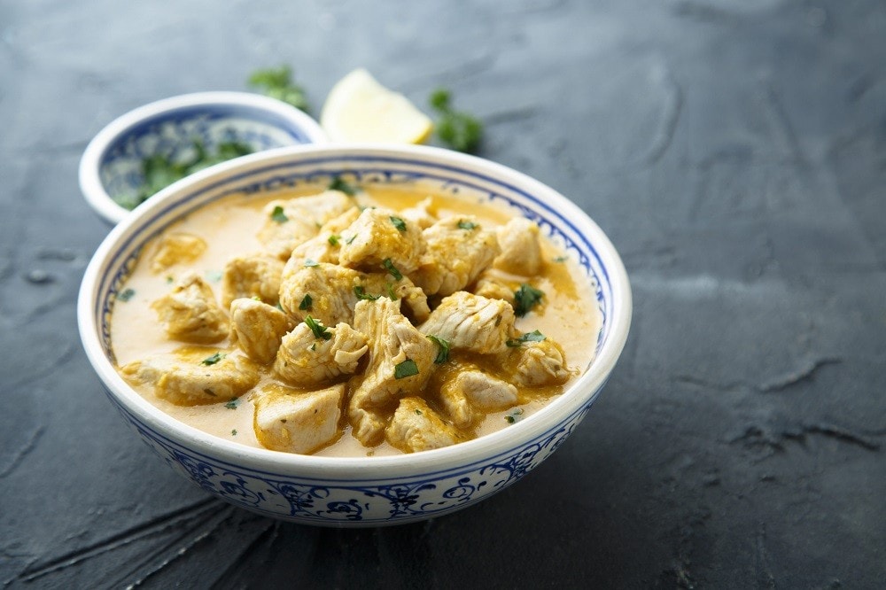 A plate of braised chicken in a creamy yellow sauce made with chicken broth A plate of braised chicken in a creamy yellow sauce made with chicken broth