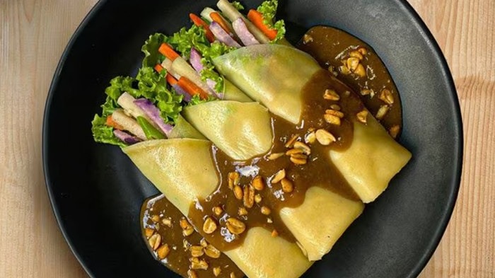Three pieces of fresh ube lumpia topped with peanut sauce. 