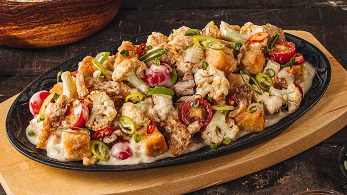 Tofu, mushroom, and cauliflower sisig served on a sizzling plate.