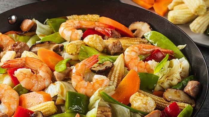 Chopsuey topped with shrimp in a wok.