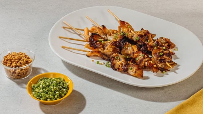 Skewered king oyster mushrooms inasal on a white platter. 