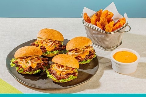 Lechon baka sliders on a gray plate with fries and dip on the side. Lechon baka sliders on a gray plate with fries and dip on the side.