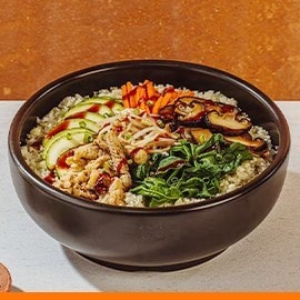 Cauliflower bibimbap in a black stone bowl with gochujang on the side.