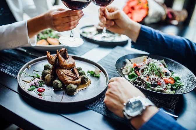 Two diners enjoying a poultry dish and a fresh salad. Two diners enjoying a poultry dish and a fresh salad.