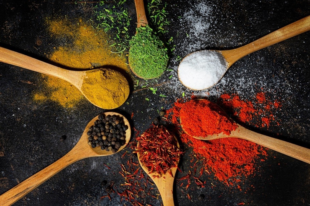 Top view of a variety powdered herbs on and around wooden spoons on a black background Top view of a variety powdered herbs on and around wooden spoons on a black background