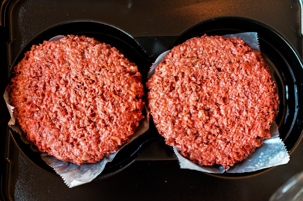 Two raw plant-based red patties in a plastic container Two raw plant-based red patties in a plastic container