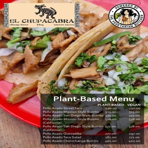 A red plate containing two plant-based tacos topped with fresh herbs. A red plate containing two plant-based tacos topped with fresh herbs.
