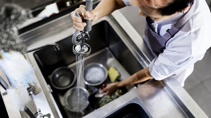 A kitchen staff washing dishes in a commercial kitchen. 