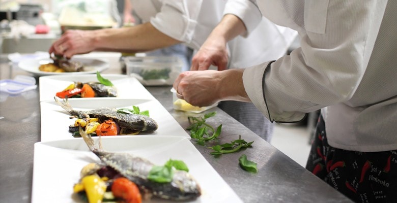 chefs plating food in kitchen