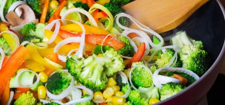 Stir-frying different vegetables, including broccoli, onions, corn kernels, and bell peppers, in a wok. Stir-frying different vegetables, including broccoli, onions, corn kernels, and bell peppers, in a wok.