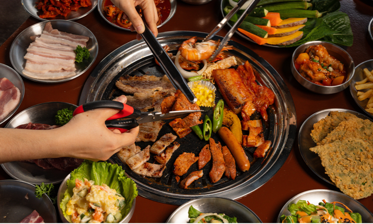 People cooking Korean bbq, showing various Korean food on the table.
