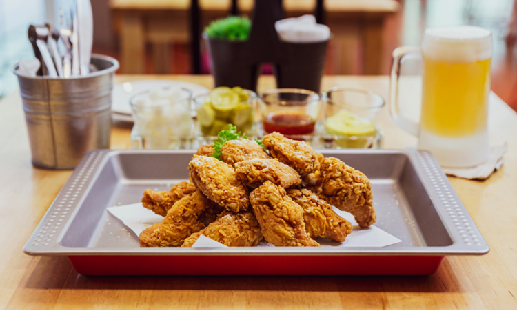 Korean fried chicken on a tray, served with side dishes and beer. 