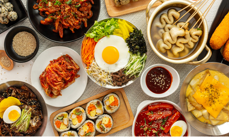 Top Korean food on a table, including bibimbap, kimbap, kimchi, and odeng.