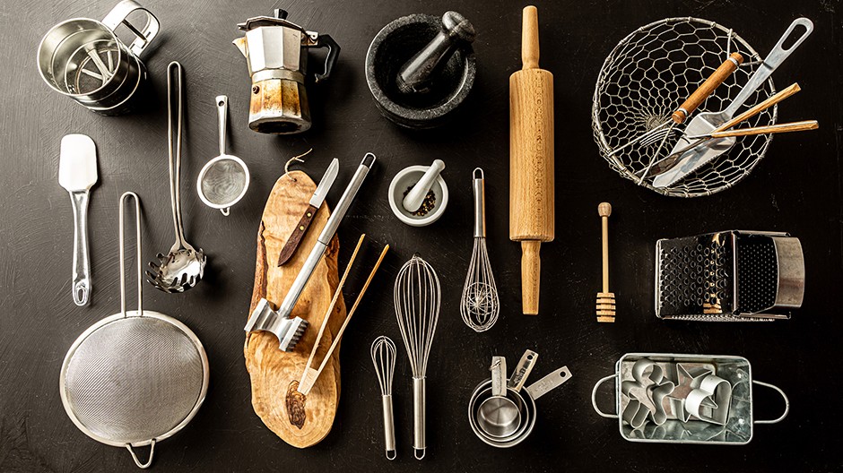 Various cookware, utensils, and smallwares on a black surface.