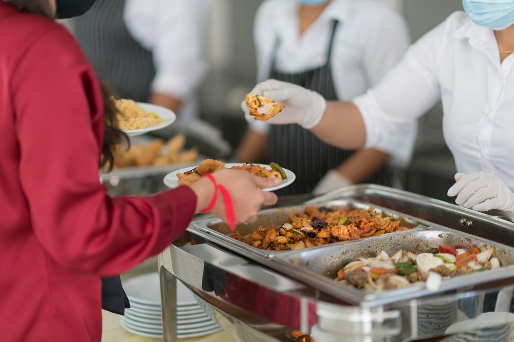 Staff can be seen serving a diner food items from the buffet Staff can be seen serving a diner food items from the buffet