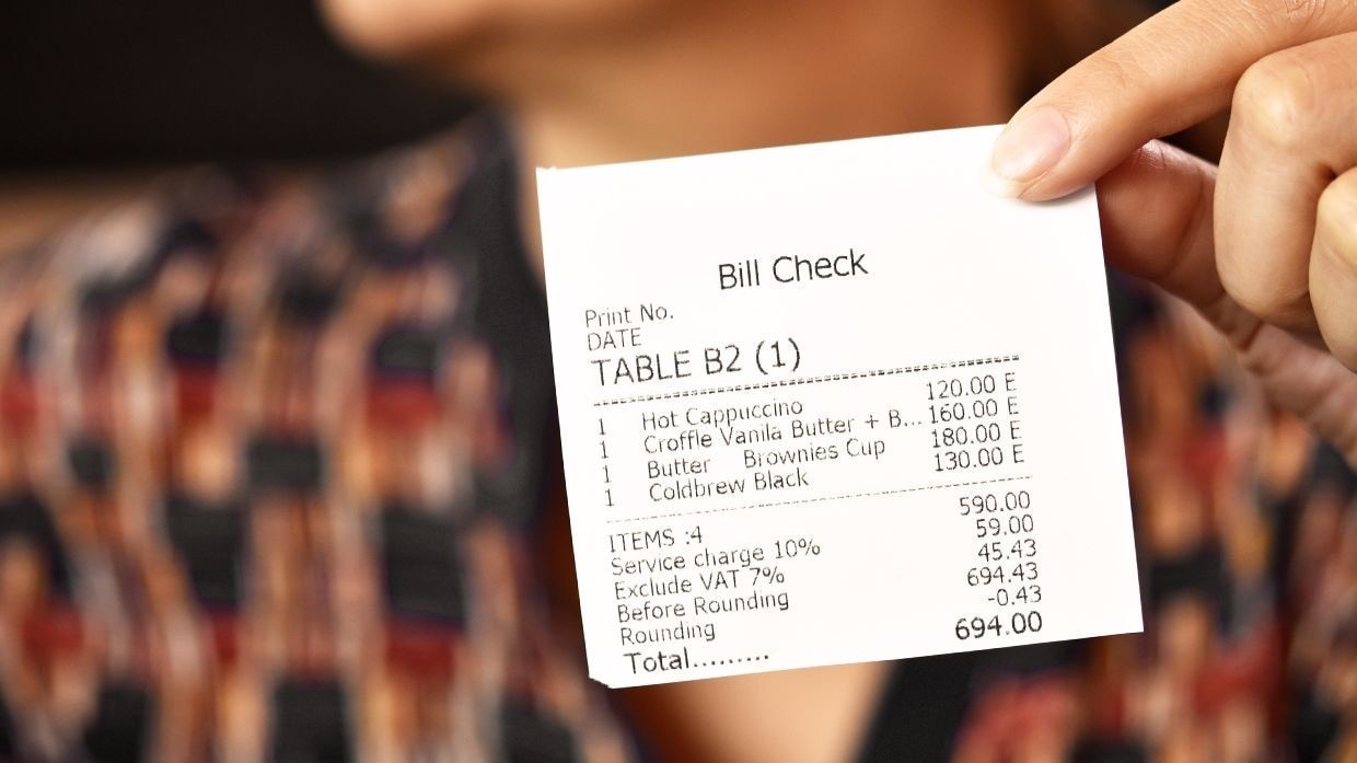 Customer holding a bill with the service charge visibly listed Customer holding a bill with the service charge visibly listed
