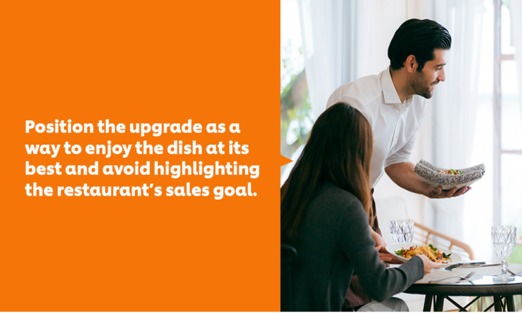 A waiter bringing food orders to a table of two female guests.