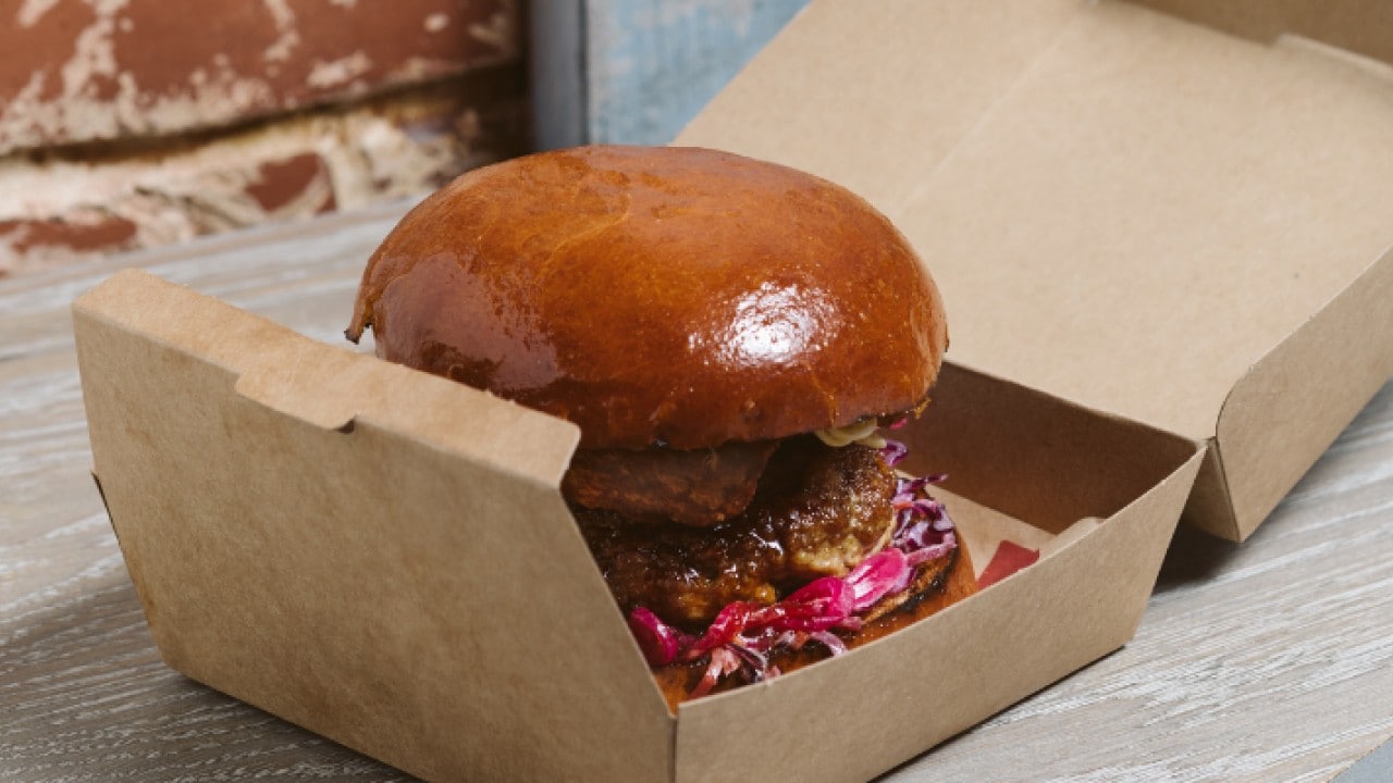 A cardboard takeout box with a hamburger. A cardboard takeout box with a hamburger.