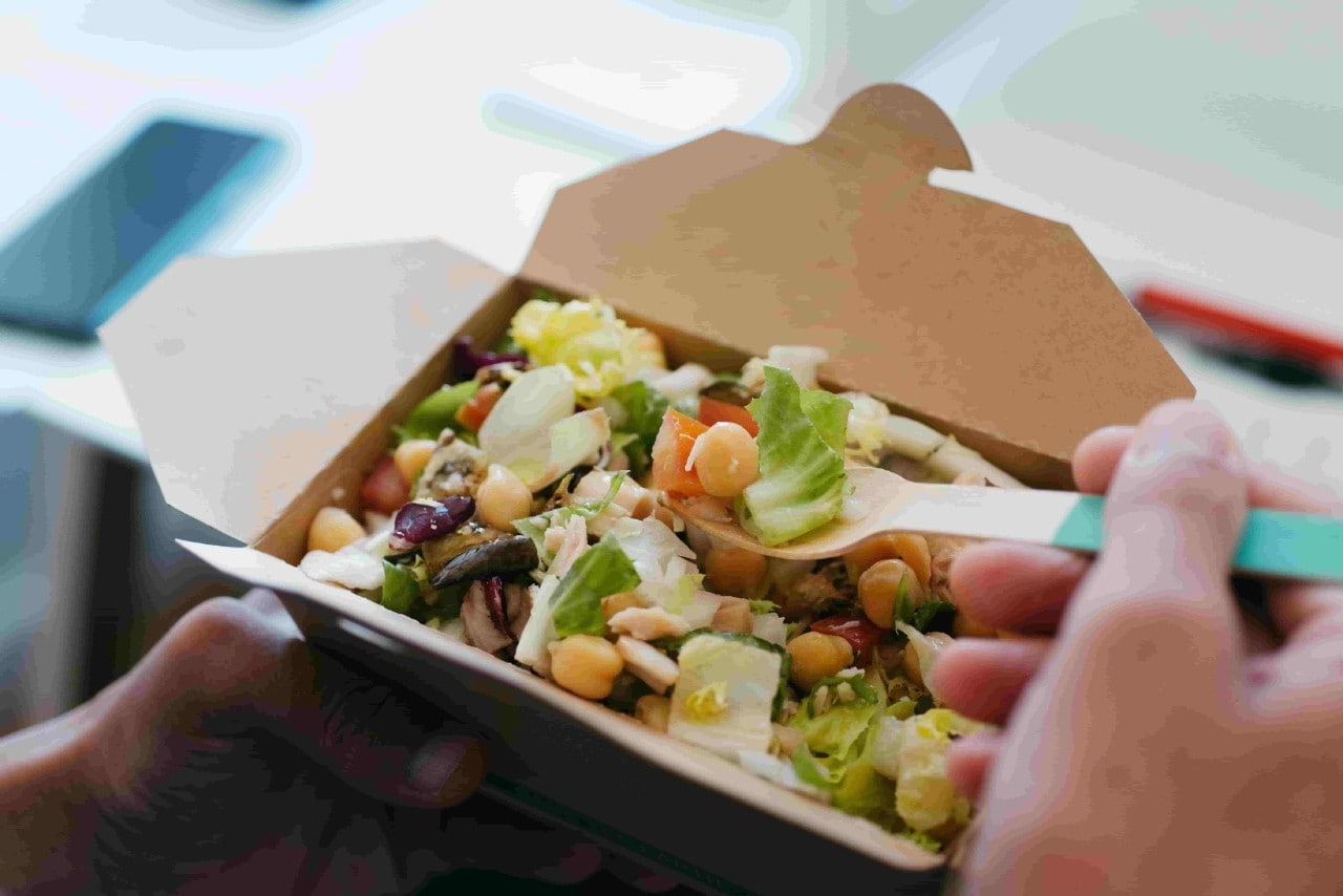 A takeout box with chickpea and greens salad. A takeout box with chickpea and greens salad.