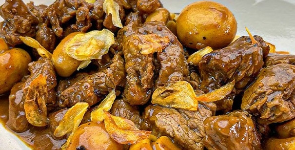 Beef salpicao with garlic chips and mushrooms in a white platter.