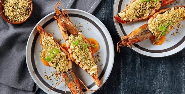 Baked prawns with cheesy filling on gray plates.