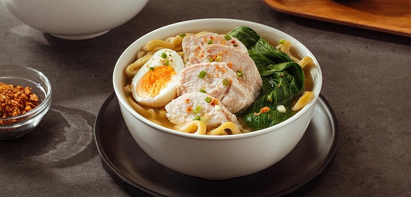 A bowl of chicken mami with egg noodles, chicken slices, bok choy, and hard-boiled egg. A bowl of chicken mami with egg noodles, chicken slices, bok choy, and hard-boiled egg.