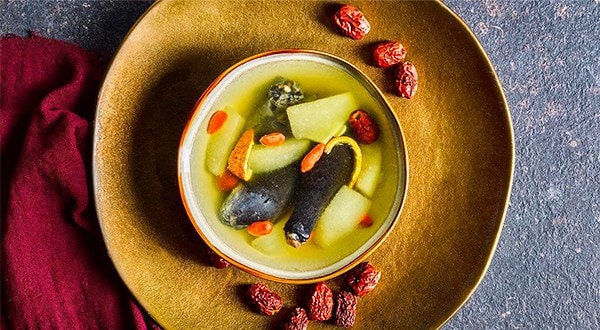 A bowl of clear soup with black chicken, pears, orange peels, and goji berries. A bowl of clear soup with black chicken, pears, orange peels, and goji berries.