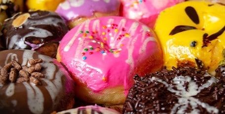 A box of mini donuts with different flavors and toppings.