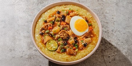 Lugaw topped with balbacua, boiled egg, and calamansi.