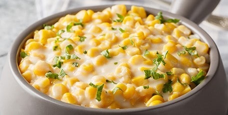 Cheesy corn kernels in a silver dish. 