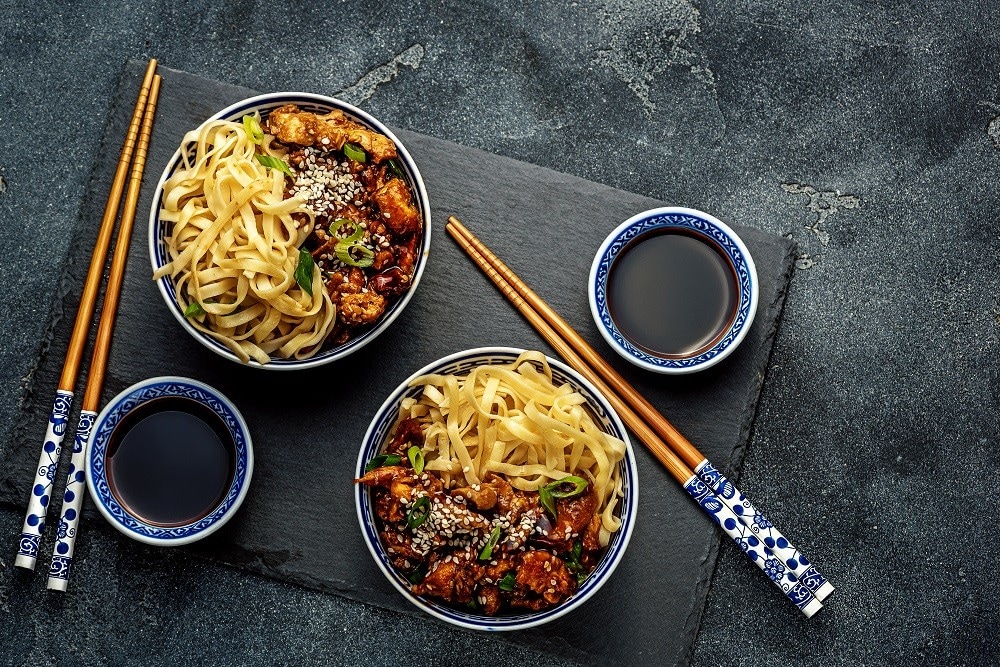 Chicken teriyaki on dark background with balsamic sauce and sesame seeds.