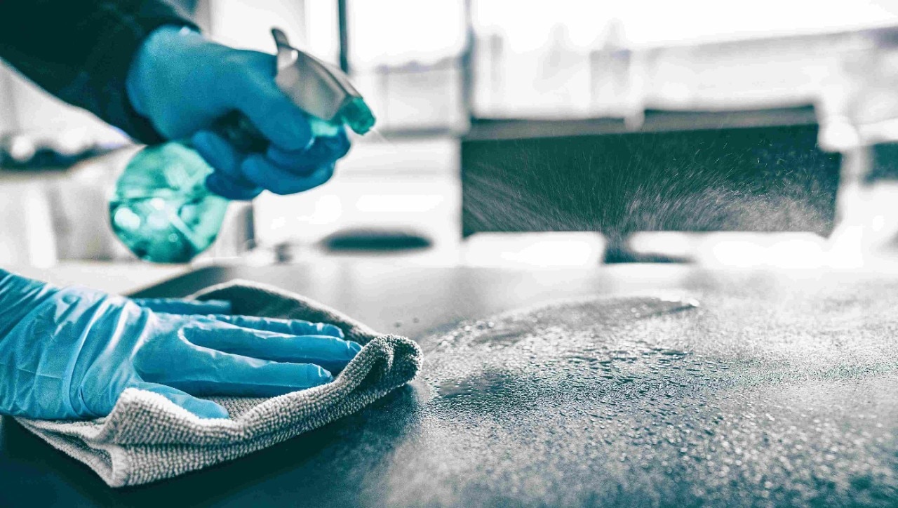Rubber gloved hands spray cleaning chemicals onto a kitchen worktop Rubber gloved hands spray cleaning chemicals onto a kitchen worktop