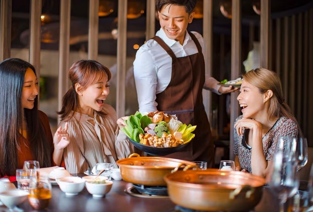 A waiter serving hot pot ingredients. A waiter serving hot pot ingredients.