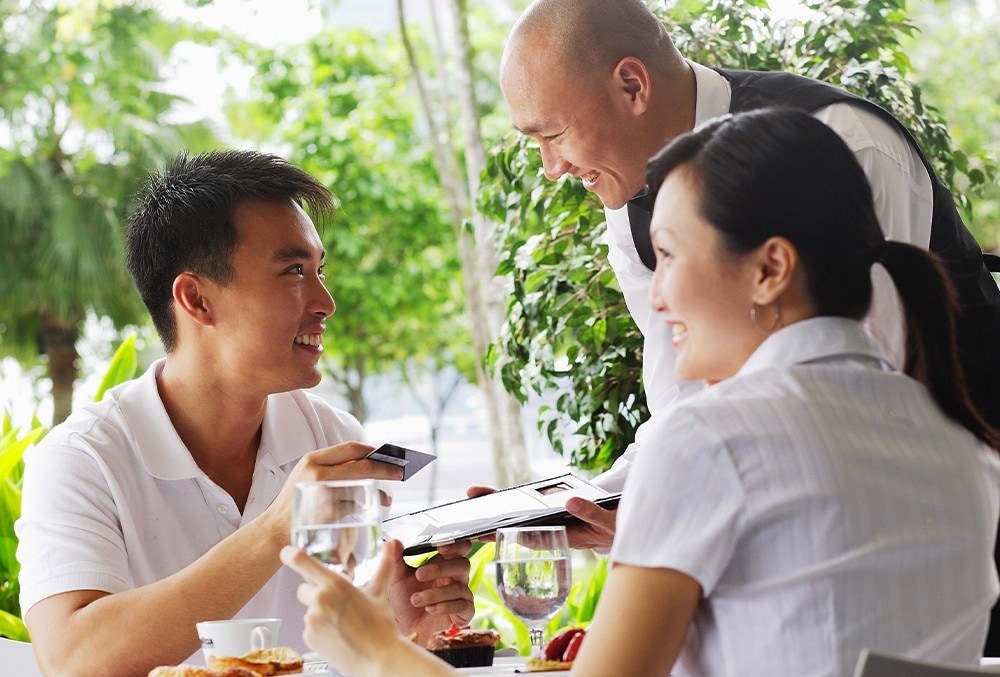 A waiter showing the bill to a customer holding a credit card. A waiter showing the bill to a customer holding a credit card.