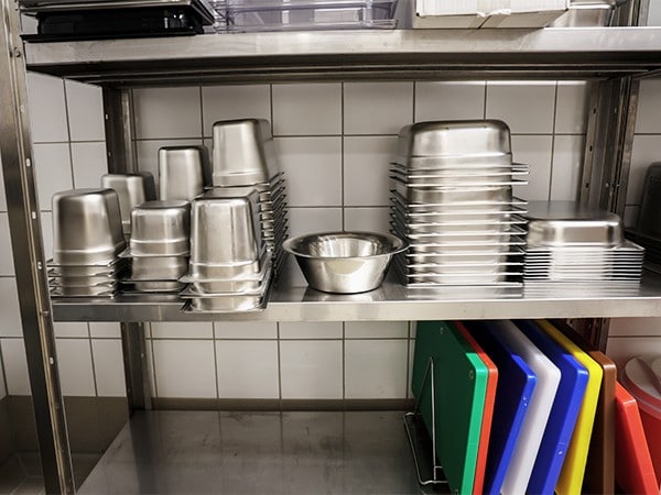 A kitchen area with stainless steel containers and color-coded chopping boards.