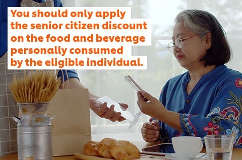 An elderly woman paying their restaurant bill via QR code. An elderly woman paying their restaurant bill via QR code.