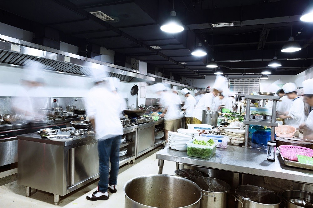 A busy commercial kitchen filled with more than 10 chefs working all at once A busy commercial kitchen filled with more than 10 chefs working all at once