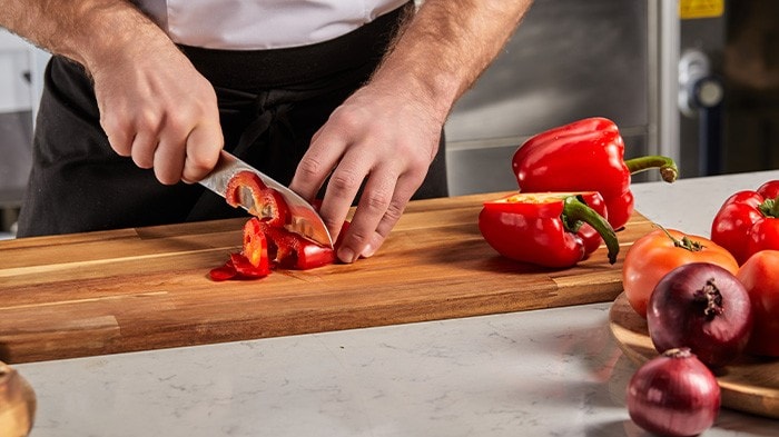 : A chef slicing red bell peppers, showing the pinch grip. 